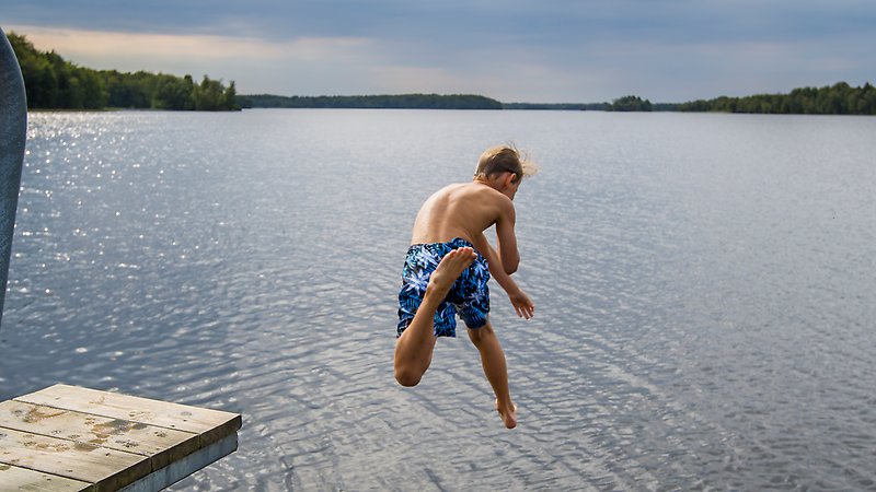 En pojke kastar sig ut från hopptornet ut i sjön