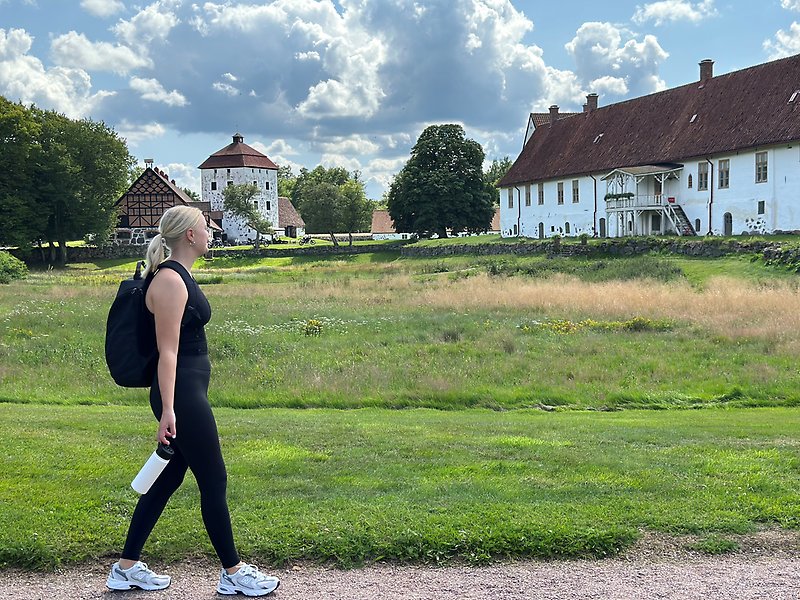 En tjej går i parken till Hovdala slott.