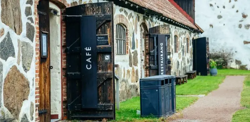 Öppna ladudörrar till ett stenhus med texten "café" skriven på insidan. 